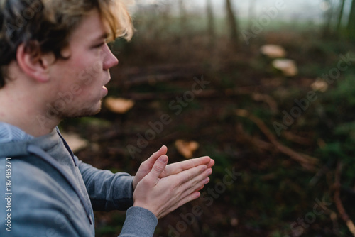 Young man rubbing hands in a forrest in Austria