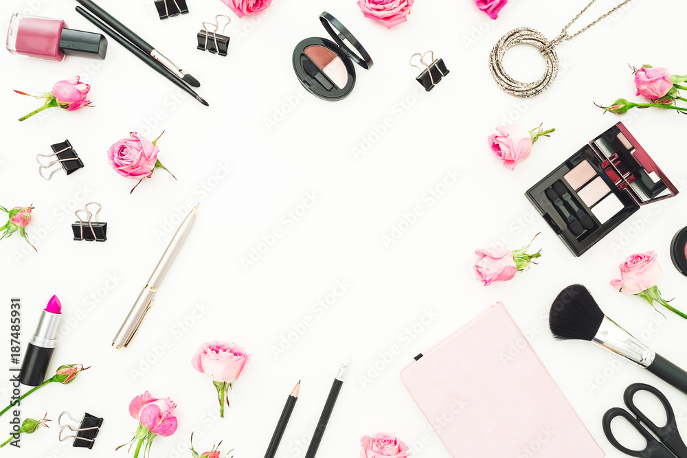 Female workspace with cosmetics, accessories and pink roses on white background. Top view. Flat lay. Beauty frame background.