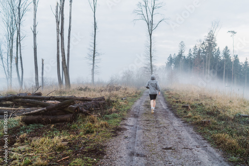 Young man running in a forrest in Austria into the fog
