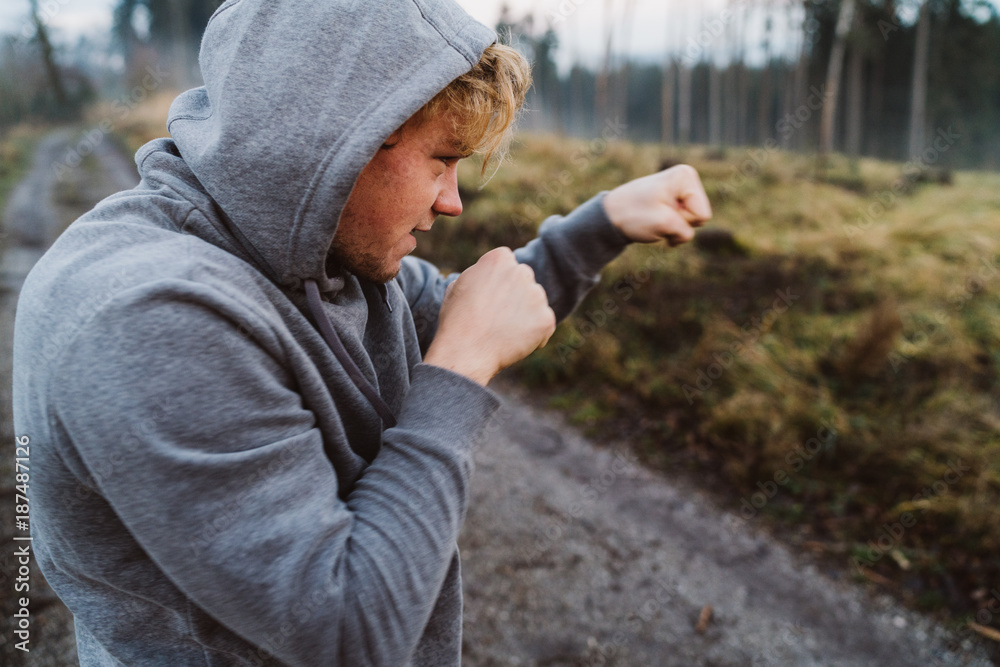 Young man shadow boxing in Austria in a forrest at sunrise Young man shadow boxing in Austria in a forrest at sunrise