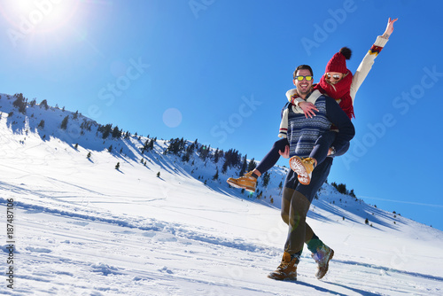Young couple having fun on snow. Happy man at the mountain giving piggyback ride to his smiling girlfriend. photo