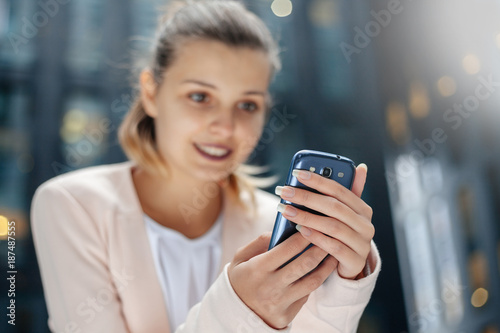 Business woman is using smartphone. Close up. City background.