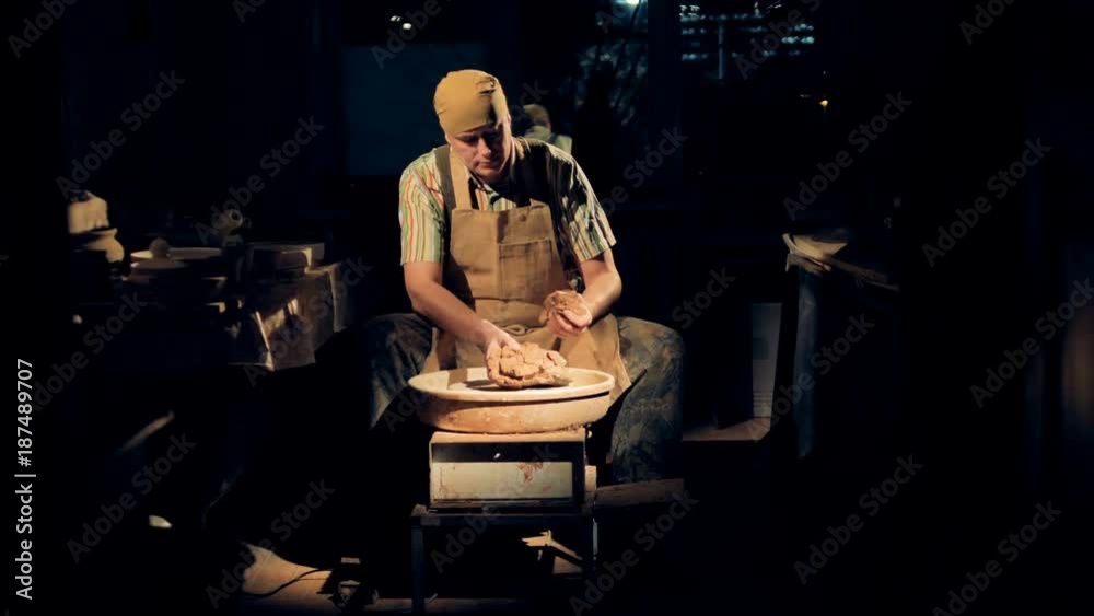 A male potter takes a small portion of clay for work. A male potter takes a small portion of clay for work.