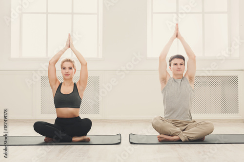 Young couple practicing yoga sitting in padmasana