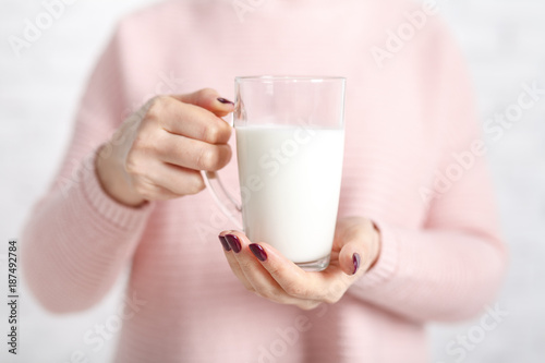 the woman is holding a glass mug of milk