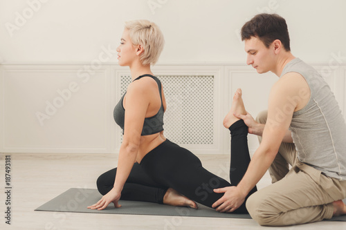 Young woman with yoga instructor in fitness club