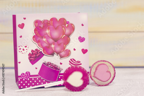 St. Valentine's gifts- a pink package with hearts and two lolipop candies with heart image. St. Valentines, anniversary, wedding concept with copy space.
