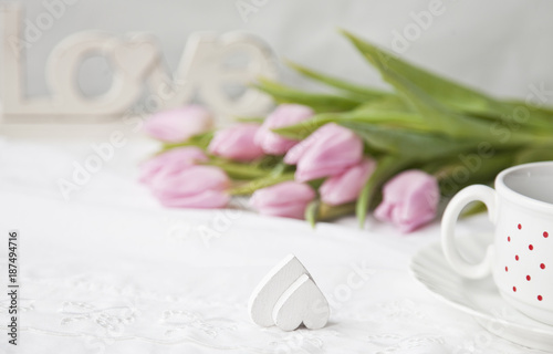 A bouquet of pink tulips and heart shape. The Valentine's Day concept, wedding, engagement and other romantic events. Top view, close-up, vintage white background