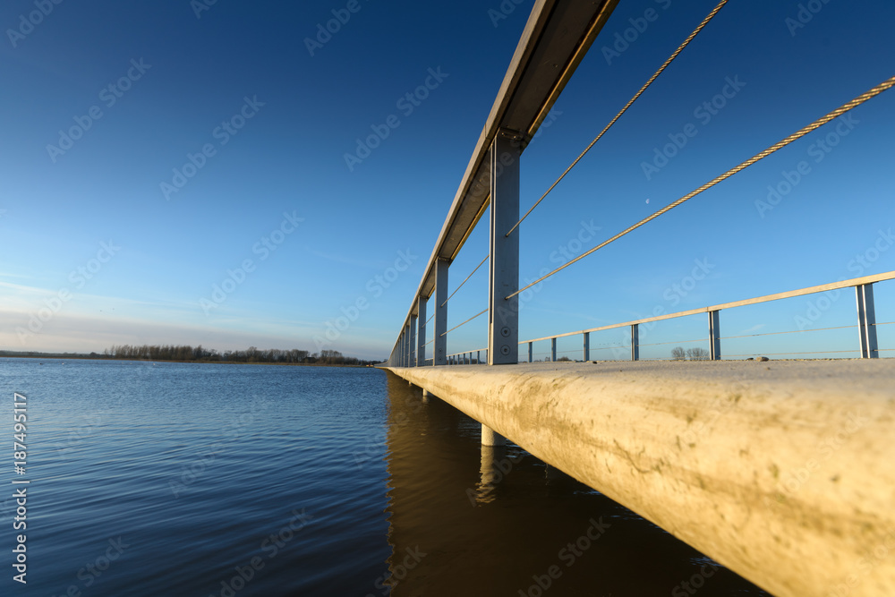 Concrete pedestrian bridge with metal railing in perspective.