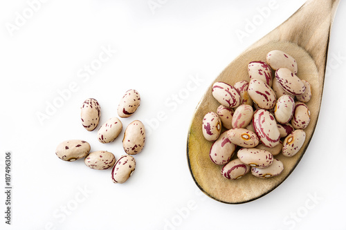 Fotografie Raw pinto beans on wooden spoon isolated on white background