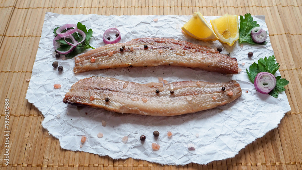 Appetizing salted herring fillet on a bamboo napkin.
Appetizing salted herring fillet on a bamboo napkin.
