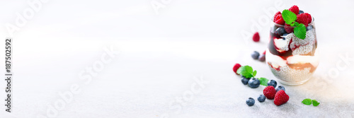 Homemade healthy chia pudding, berries, raspberries, blueberries, mint, almond milk in a glass. Copy space. Banner © jchizhe