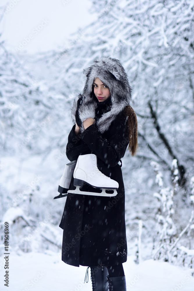 Girl with pair of figure skates at trees in snow Girl with pair of figure skates at trees in snow