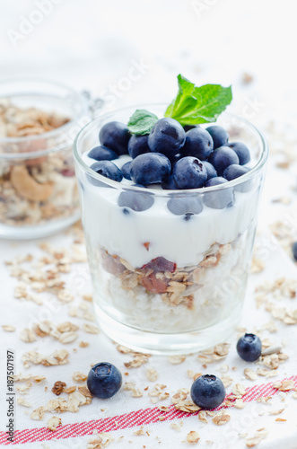 Top view healthy breakfast of homemade granola cereal with blueberries, nuts and fruit, honey with drizzlier background. Morning food, Diet, Detox, Vegetarian concept.