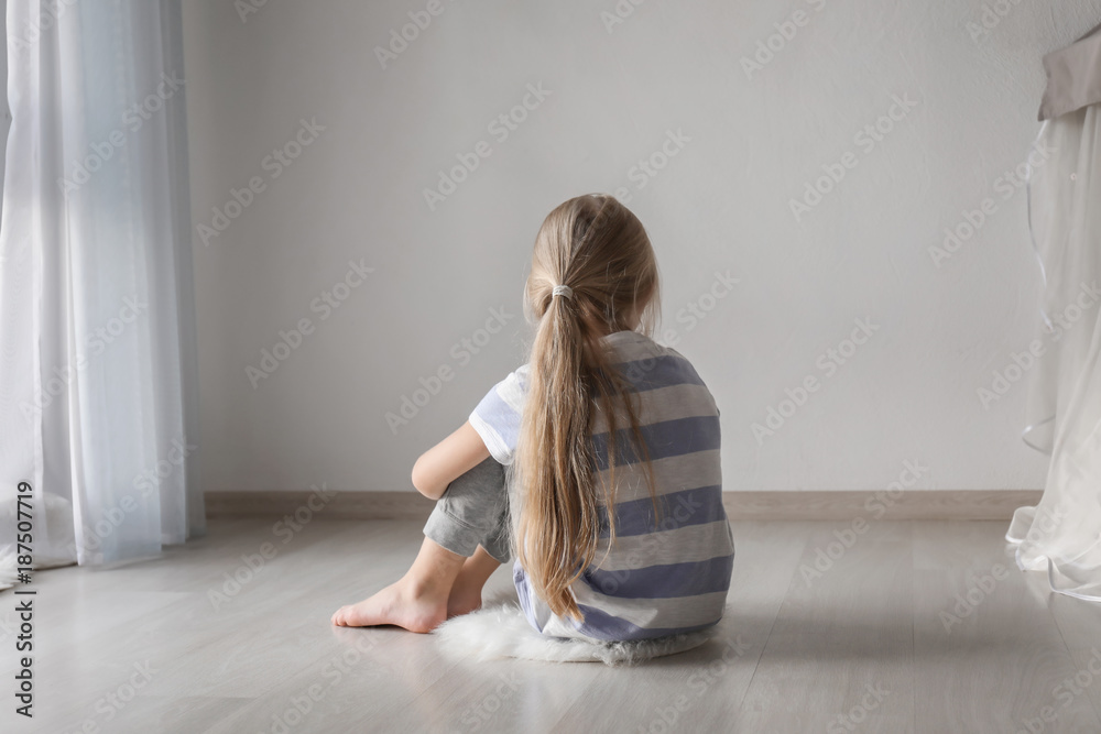 Little girl sitting on floor in room. Autism concept Little girl sitting on floor in room. Autism concept