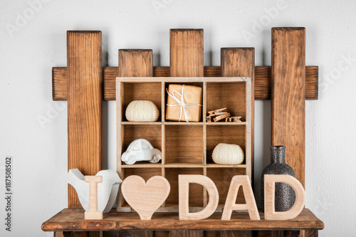 Phrase "I love dad" made of wooden letters on shelf. Father's Day celebration