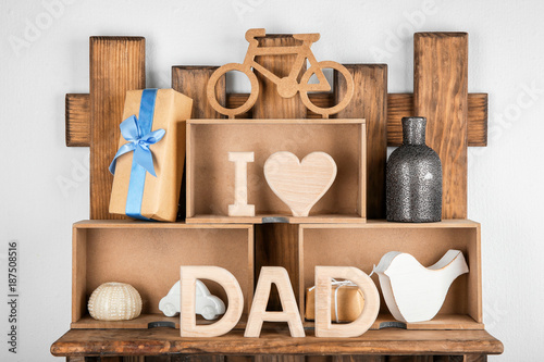Composition with phrase "I love dad" made of wooden letters on shelves. Father's Day celebration