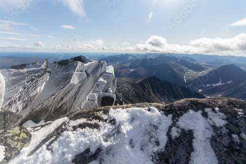 snowy rocks in the foreground and the huge mountain in the background in the mountains of the Subpolar Urals