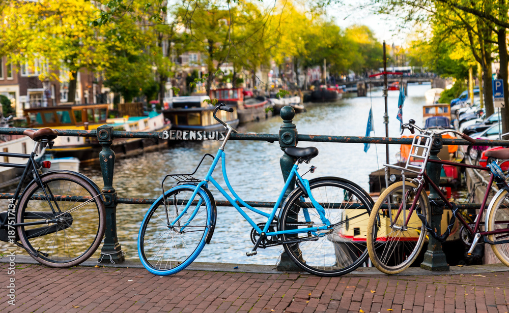 Blue vintage bike parked on a bridge over the canal in Amsterdam, Holland.