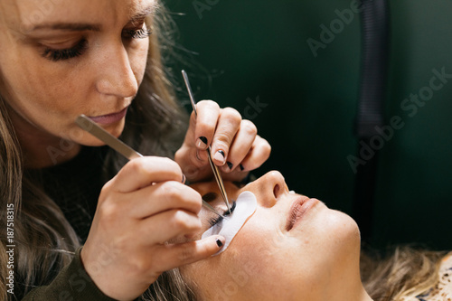 Young woman getting lash extension cosmetology laying down in small business studio