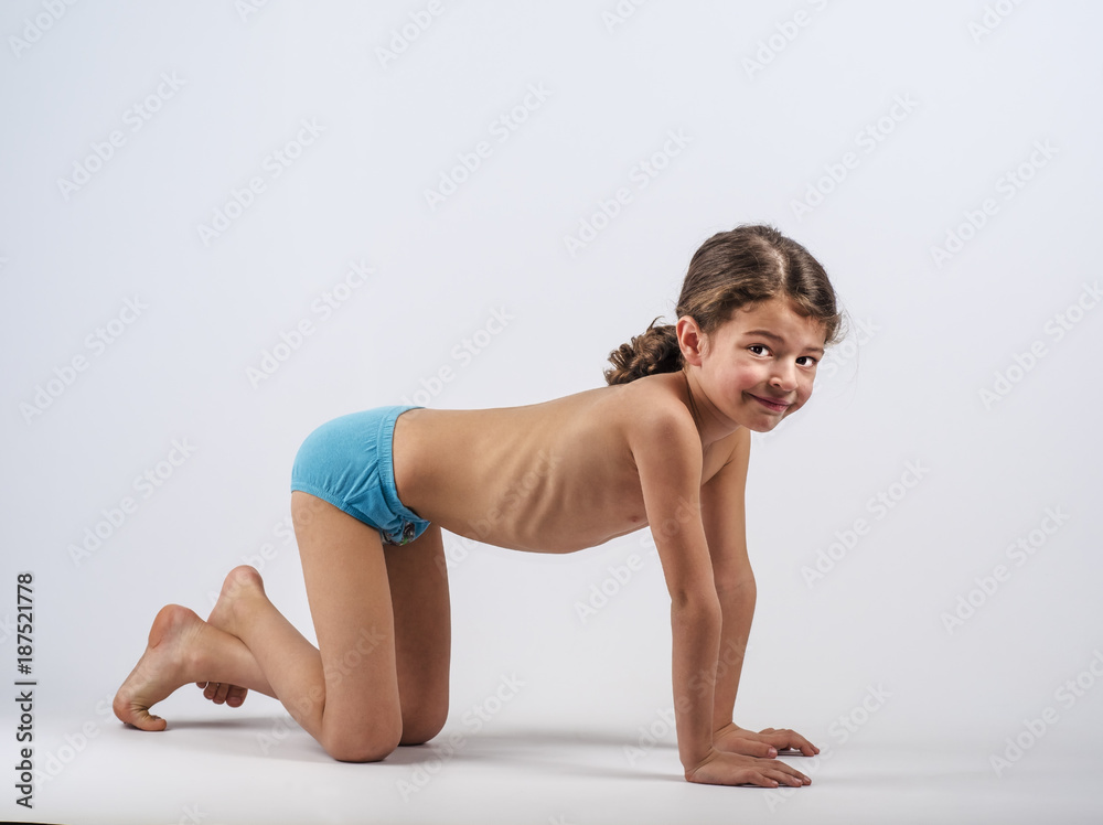 Cute boy in swimming trunks doing gymnastic exercises. Gray background. Cute boy in swimming trunks doing gymnastic exercises. Gray background.
