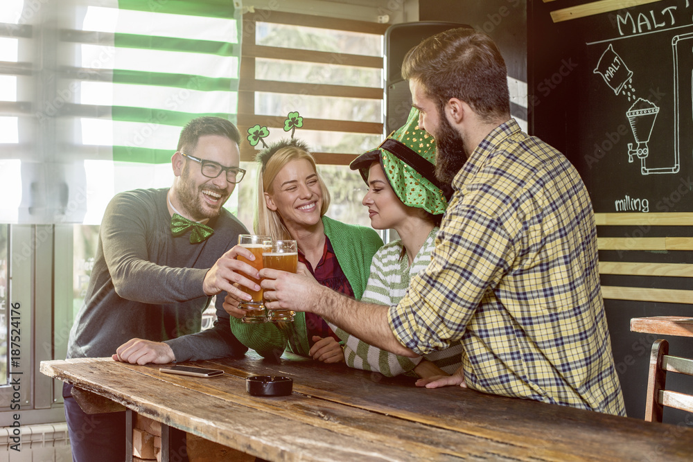 Four friends celebrate St Patrick day in pub  and dring a beer and smile