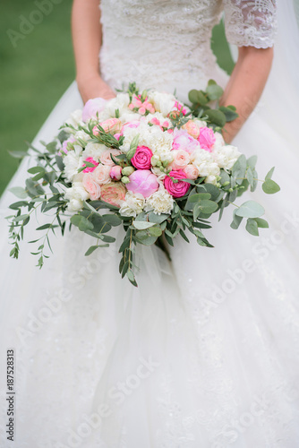 Gorgeous bride holds pink bouquet standing outside