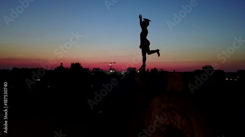Zooming in on Statue of Mercury Diety on Mercur Palace, historical building in Piata Traian overlooking twilight in Timisoara, Romania.