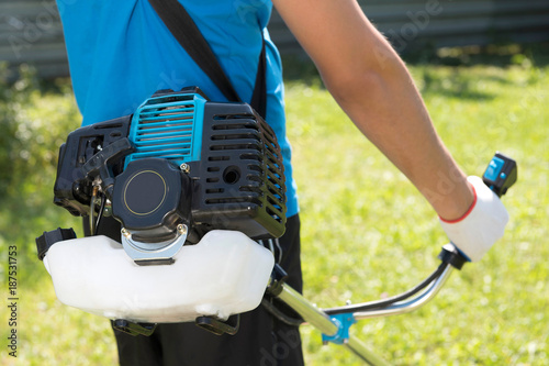 The man cutting a grass with the lawn mower. Closeup.