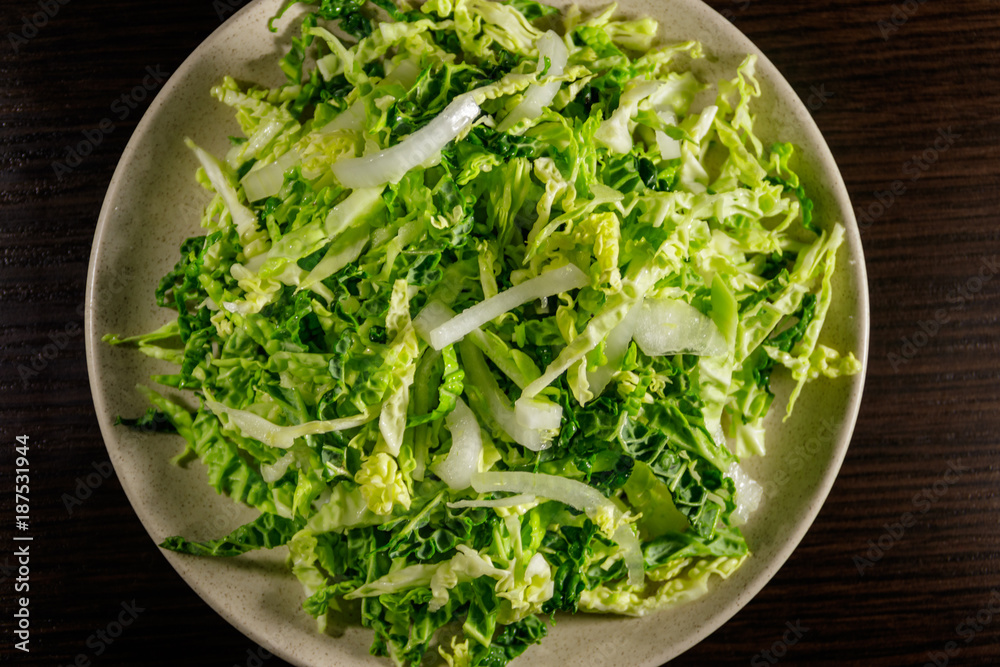 Salad with savoy cabbage and onion on wooden table Salad with savoy cabbage and onion on wooden table