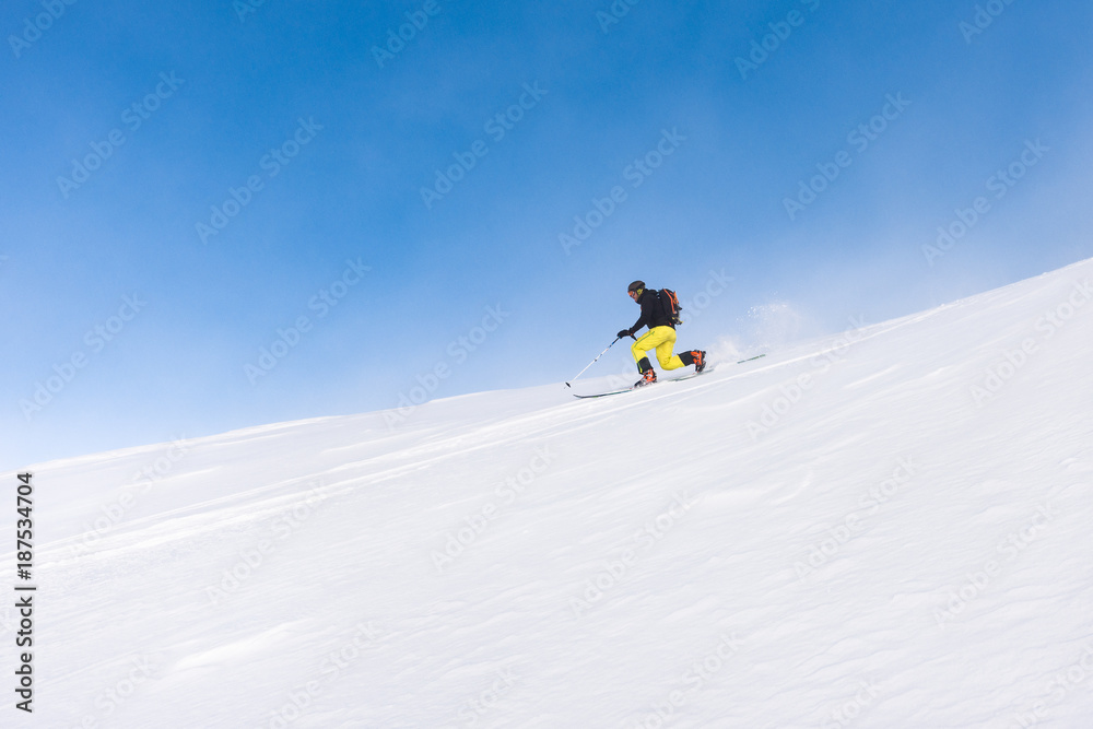 Man skiing telemark style on steep slope on a bright day Man skiing telemark style on steep slope on a bright day