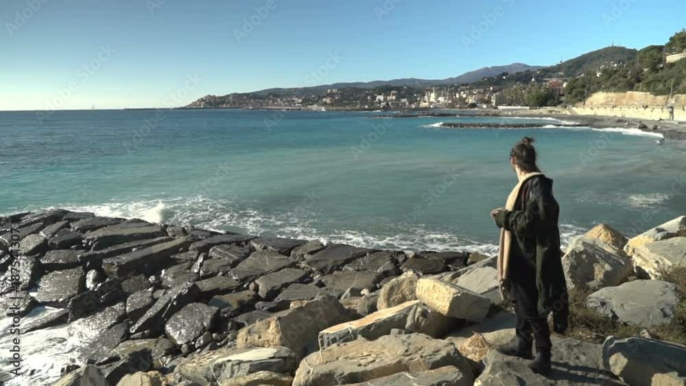 Young man standing on some rocks, gazing at the sea. Young man standing on some rocks, gazing at the sea.
