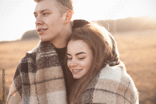 Young man and woman standing under a blanket on a field