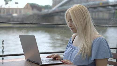 Pretty girl sitting on the boat and using modern notebook
