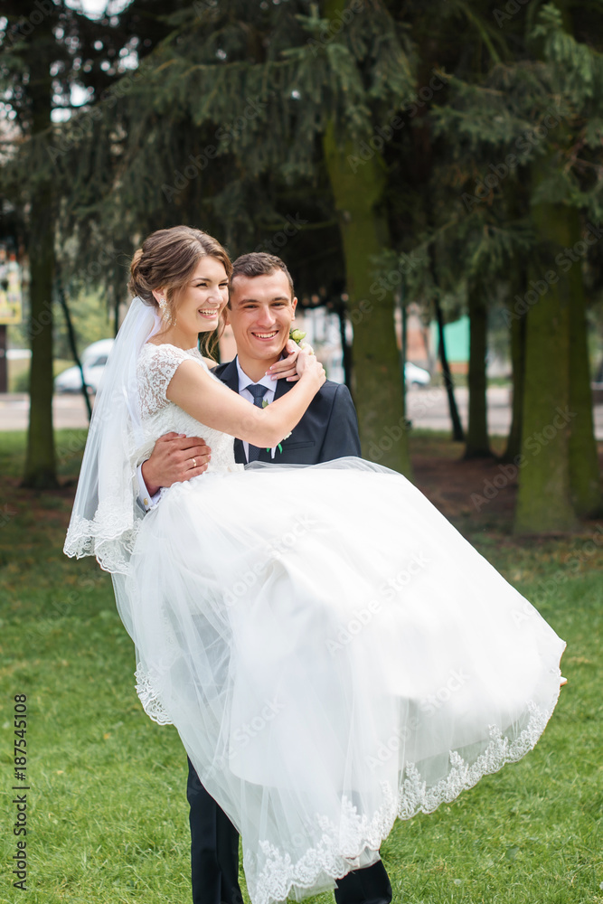 Just married couple dancing valse outdoor, free space. Bride and groom hugs, blurred green grass background. First wedding dance concept