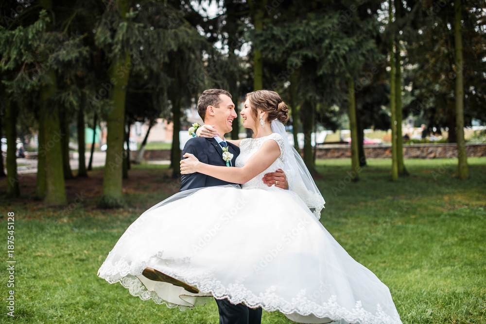 Just married couple dancing valse outdoor, free space. Bride and groom hugs, blurred green grass background. First wedding dance concept