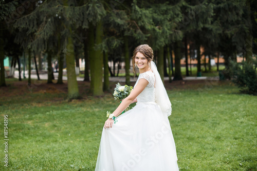 Handsome gorgeous bride in white wedding dress with bridal bouquet