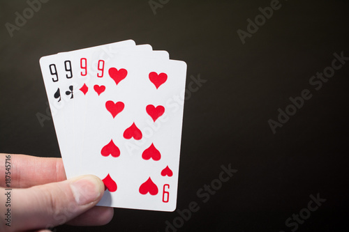 Fotografie Abstract: man hand holding playing card four nine isolated on black background w