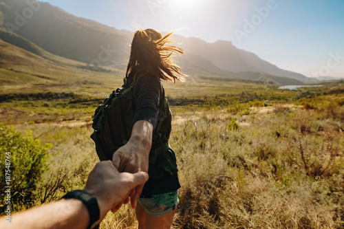 Woman holding man's hand and leading him on hiking trail