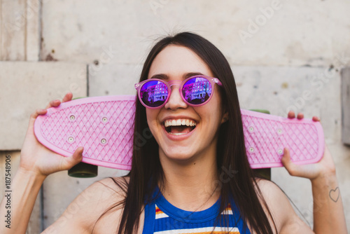 Happy woman with pink vintage skateboard and sunglasses