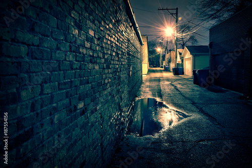 Vintage brick wall in a dark, gritty and wet Chicago alley at night after rain.