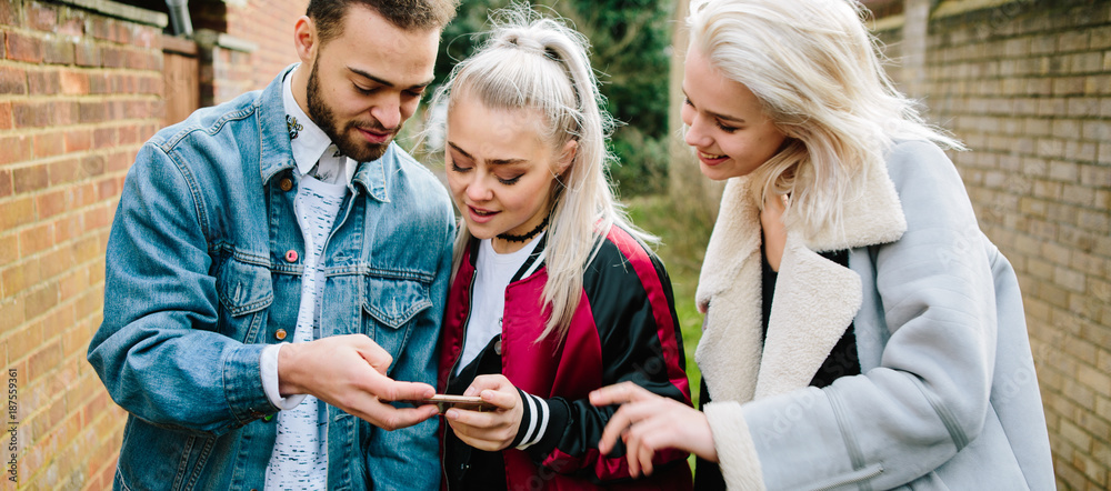 Three teenagers walking around and using their phones Three teenagers walking around and using their phones
