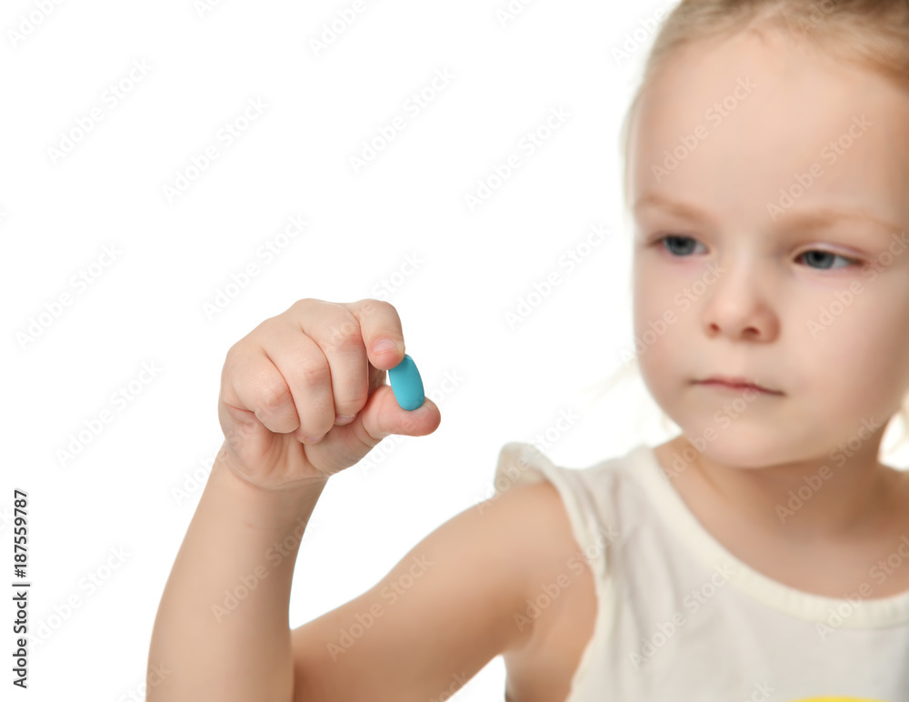 Young baby girl hold light blue headache pill medicine tablet in small hand Young baby girl hold light blue headache pill medicine tablet in small hand