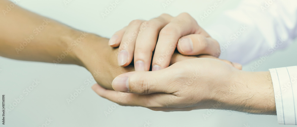 Obraz premium Two people holding hands for comfort. Doctor consoling relatives of patients in hospital concept banner panoramic crop for copy space.