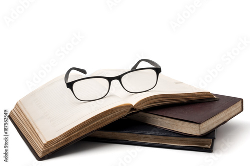 A stack of old books with eyeglasses on a white background.