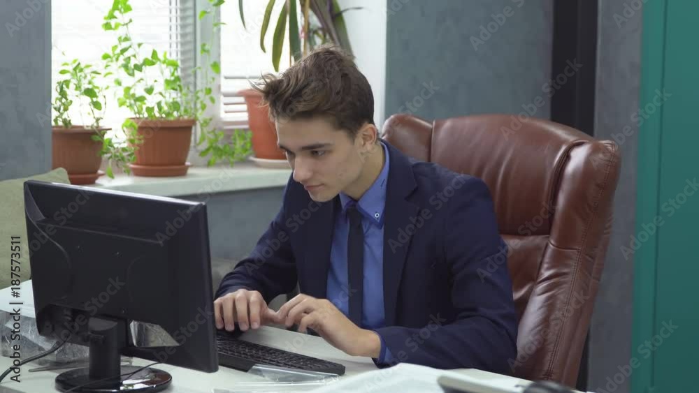 Successful young man in formal suit working at computer evaluating risks and forecasts Successful young man in formal suit working at computer evaluating risks and forecasts
