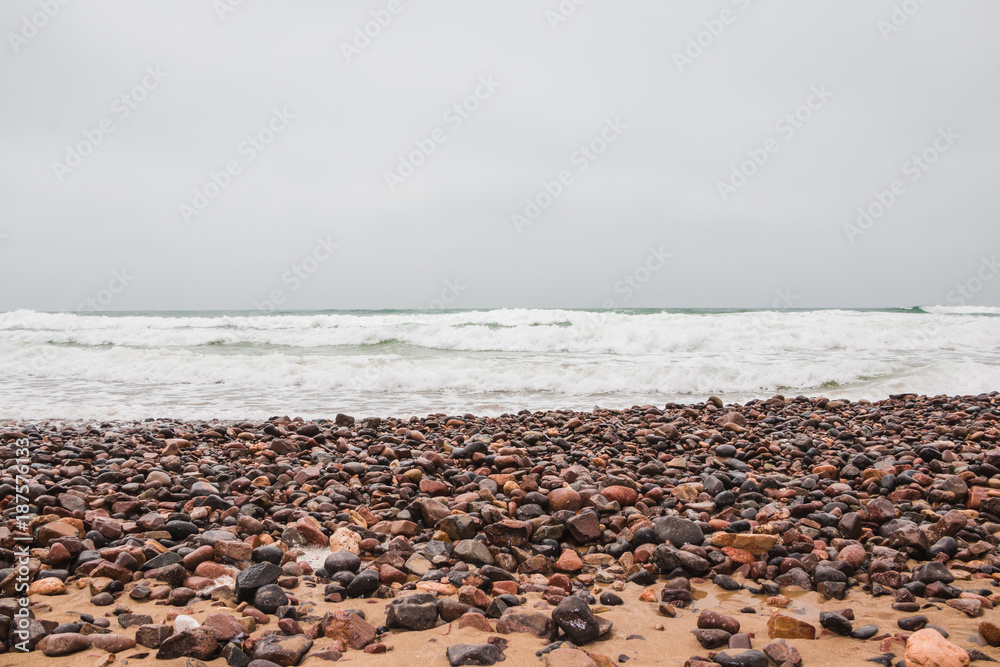 Coast, waves and beach with yellow sand and pebbles