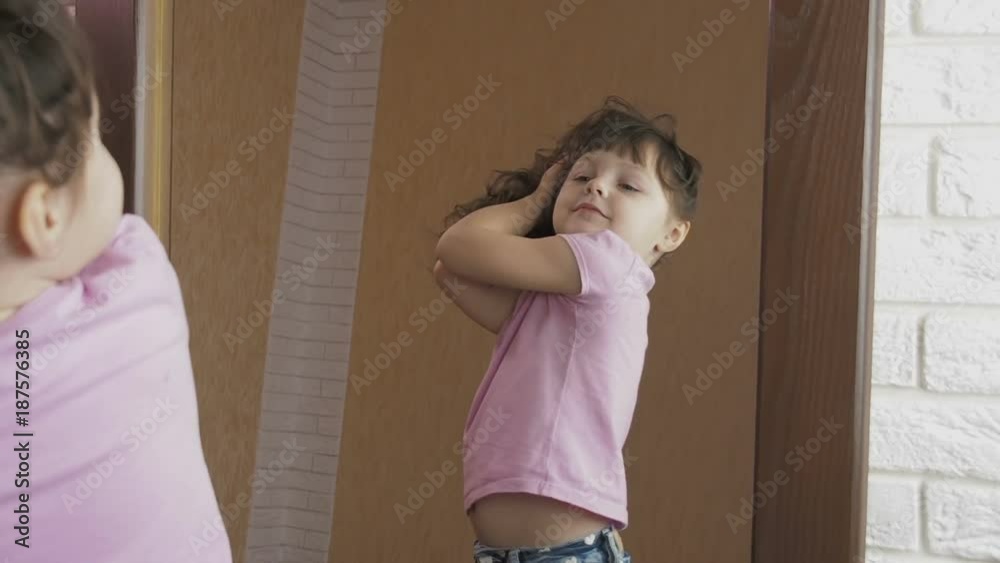 A child in front of a mirror. A beautiful little girl looks into her reflection in the mirror.