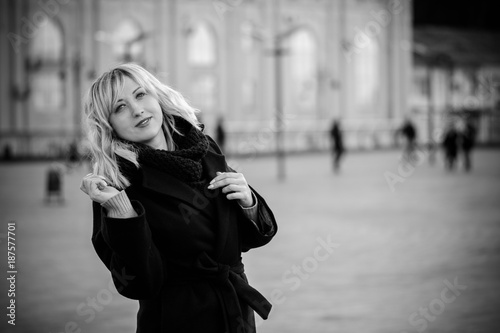 Beautiful nice middle age business woman with blond hair at evening walk at the city with romantic mood. Lady wearing in dark coat and scarf. Young woman walking on a city street 