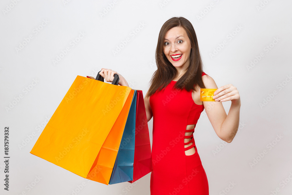 Attractive glamour fashionable young brown-hair woman in red dress holding credit card, multi colored packets with purchases after shopping isolated on white background. Copy space for advertisement. Attractive glamour fashionable young brown-hair woman in red dress holding credit card, multi colored packets with purchases after shopping isolated on white background. Copy space for advertisement.